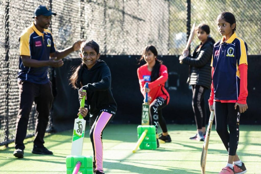 Kenroy Peters with YPCC girls cricket players