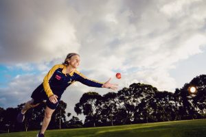 Woman cricketer leaning to catch ball