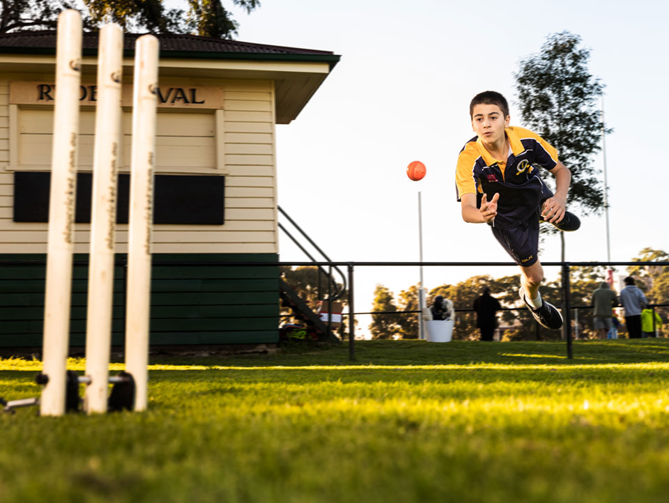 Young boy jumps to catch cricket ball